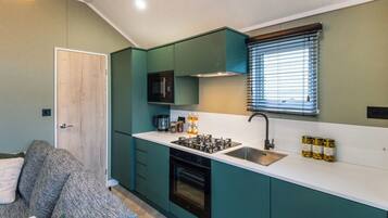 Une cuisine de taille réduite avec des meubles de couleur turquoise, un four à micro-ondes, une cuisinière et un évier.