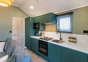 Une cuisine de taille réduite avec des meubles de couleur turquoise, un four à micro-ondes, une cuisinière et un évier.
