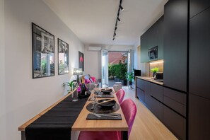 A modern dining area with a wooden table, black placemats, and pink chairs. - GuestHost - 50 sqm apartment for 3 people, tastefully furnished, located in the quiet Corridoni area of Bergamo. The apartment features a private garden and a reserved parking space for guests, ensuring maximum convenience for those traveling by car. Ide (Bergamo)