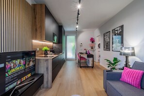 A modern living room with a TV, sofa, and dining area. - GuestHost - 50 sqm apartment for 3 people, tastefully furnished, located in the quiet Corridoni area of Bergamo. The apartment features a private garden and a reserved parking space for guests, ensuring maximum convenience for those traveling by car. Ide (Bergamo)