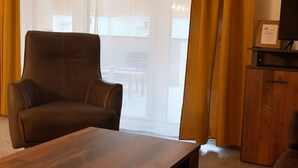 A room with a brown leather armchair, a wooden coffee table, and a wooden cabinet with a framed certificate.