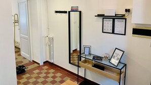 A hotel room with a check-in counter, a mirror, a framed 'House Rules' sign, a 'Guest Book', and a 'WiFi' sign.