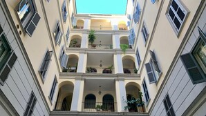A multi-story building with balconies, arched windows, and potted plants.