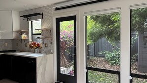 Eine moderne Küche mit Marmorarbeitsplatte, eingebauten Regalen und einem Fenster mit Blick auf einen Garten.