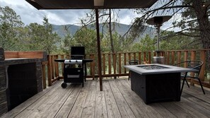 An outdoor deck with a grill, a table, and a fire pit.