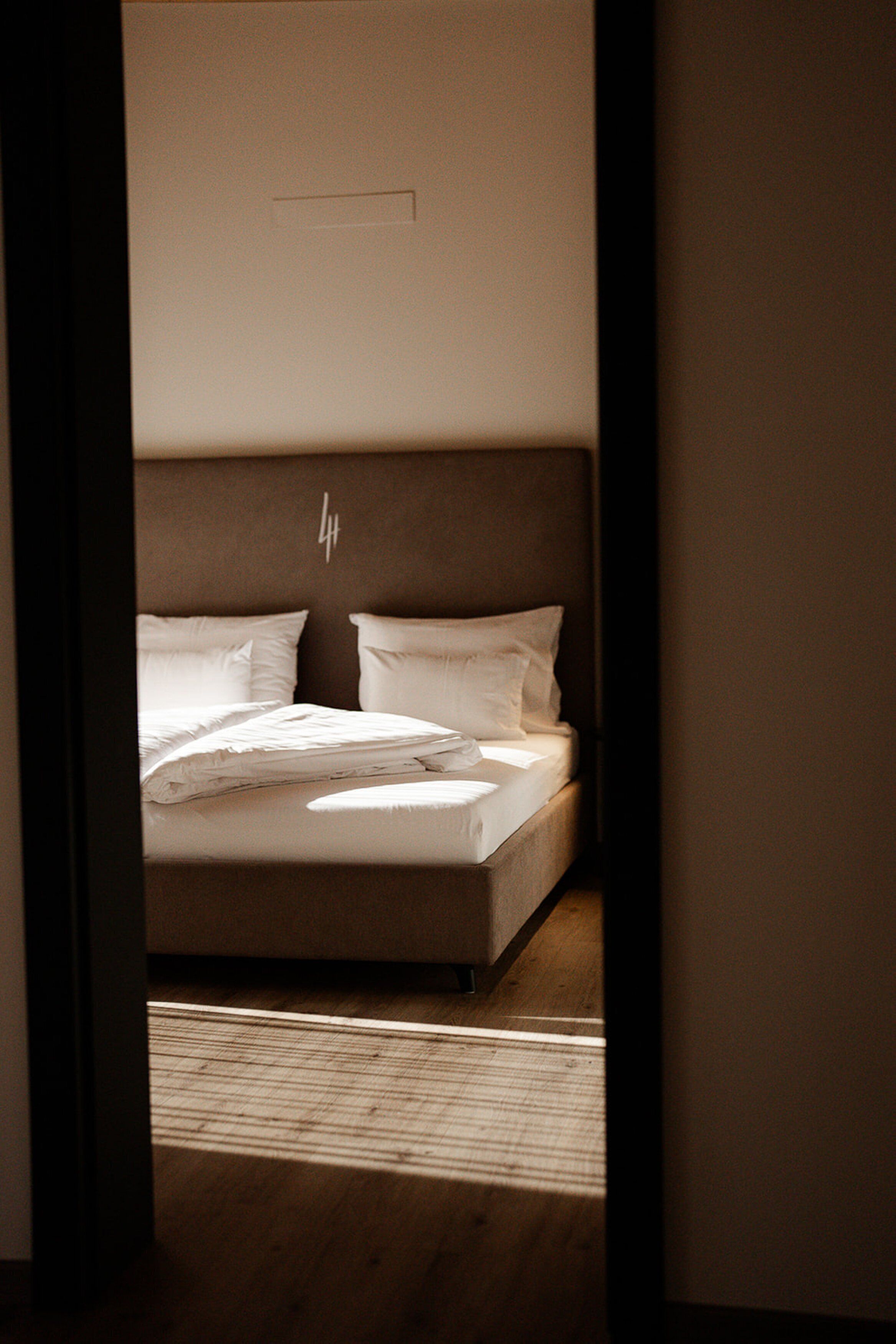 A bedroom with a bed, pillows, and a headboard.