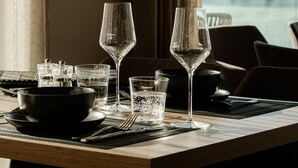 A dining table with a view of a snowy landscape through a window. - LH Linzerhaus Suites Saalbach – inklusive Jokercard (Saalbach-Hinterglemm)