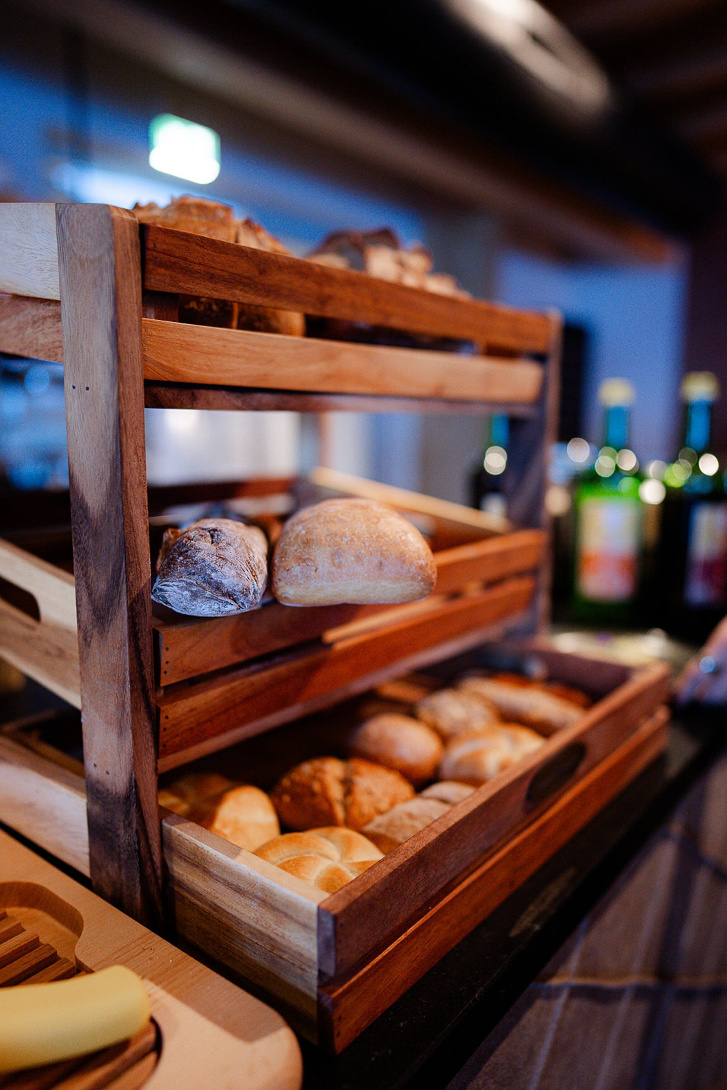 A wooden bread display with various types of bread.