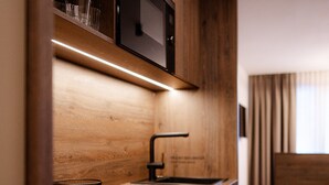A modern kitchen with wooden cabinets, a microwave, and a sink. - LH Linzerhaus Suites Saalbach – inklusive Jokercard (Saalbach-Hinterglemm)