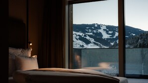 A hotel room with a large window offering a view of snow-covered mountains. - LH Linzerhaus Suites Saalbach – inklusive Jokercard (Saalbach-Hinterglemm)