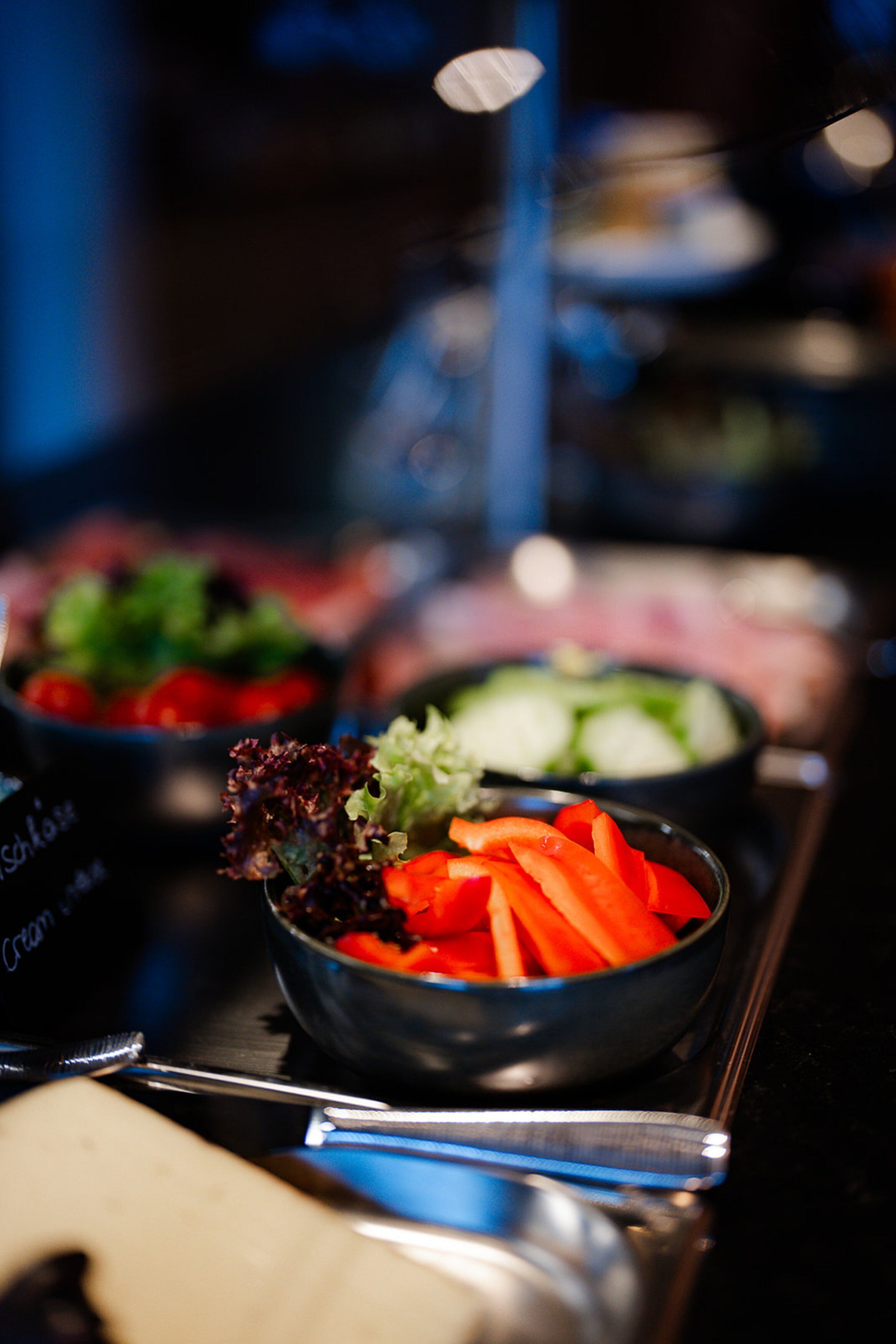 Uma mesa de buffet com diversos pratos, incluindo uma saladeira de cenouras fatiadas e uma salada.