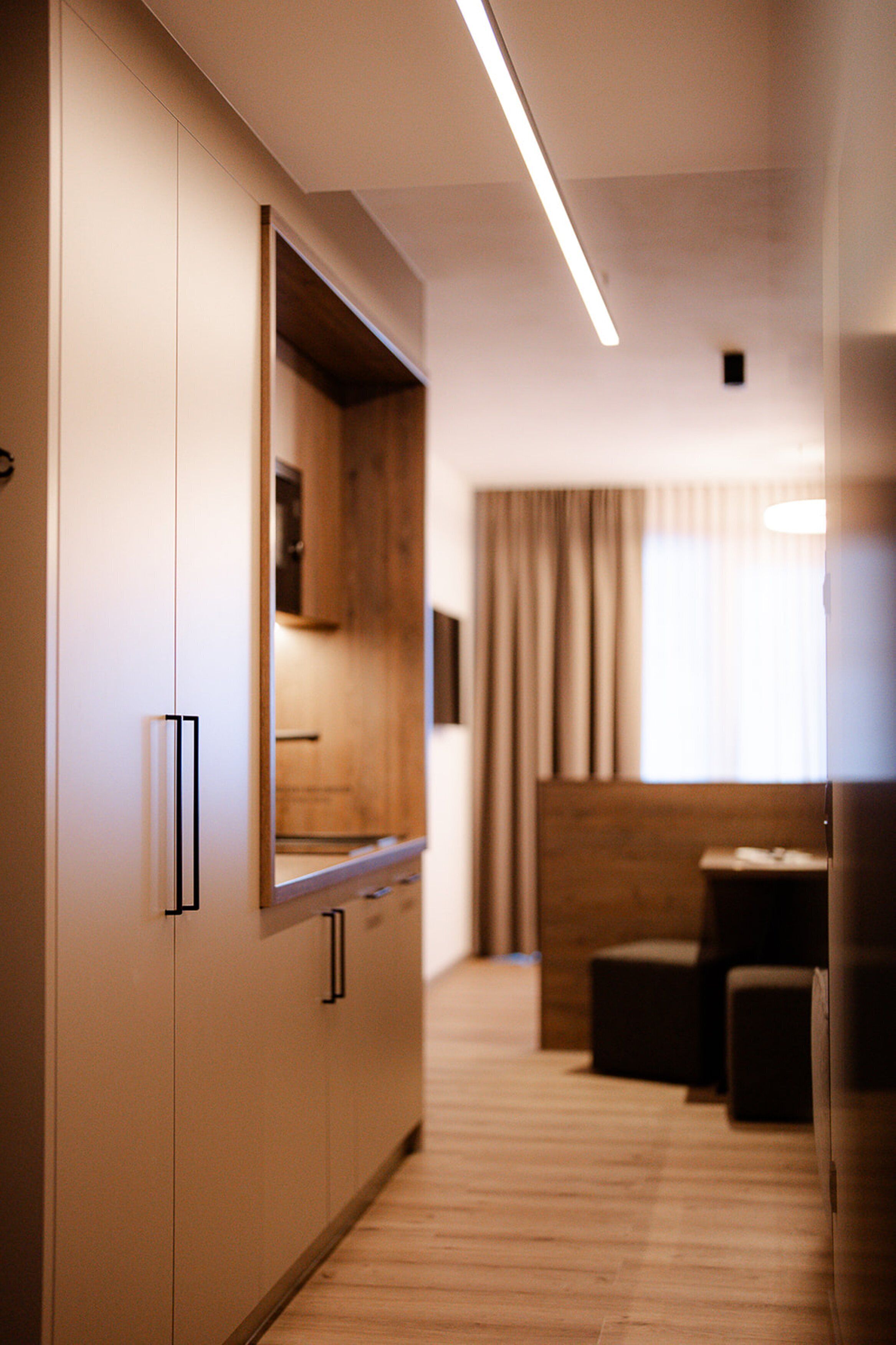 Ein moderner Hotelkorridor mit Holzboden, einer integrierten Küchenzeile und einer Sitzecke mit Blick ins Freie.
