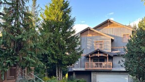 A two-story building with a wooden exterior, a balcony, and a garage. - Bluff 9 townhouse with beautiful view (Whistler)