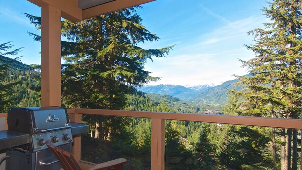 A balcony with a grill and a view of a forested mountain range. - Bluff 9 townhouse with beautiful view (Whistler)