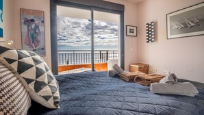 A bedroom with a large bed, a view of the sea, and a balcony.