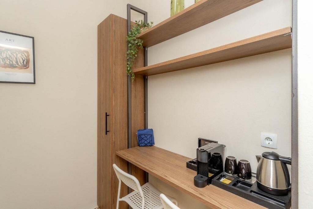 Een kleine kitchenette met een koffiezetapparaat, kopjes en een waterkoker op een houten aanrecht.