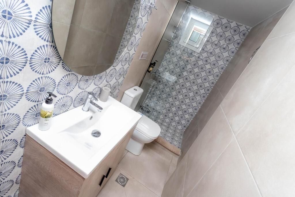 Une salle de bain avec un lavabo, des toilettes et une douche, le tout de couleur blanche.