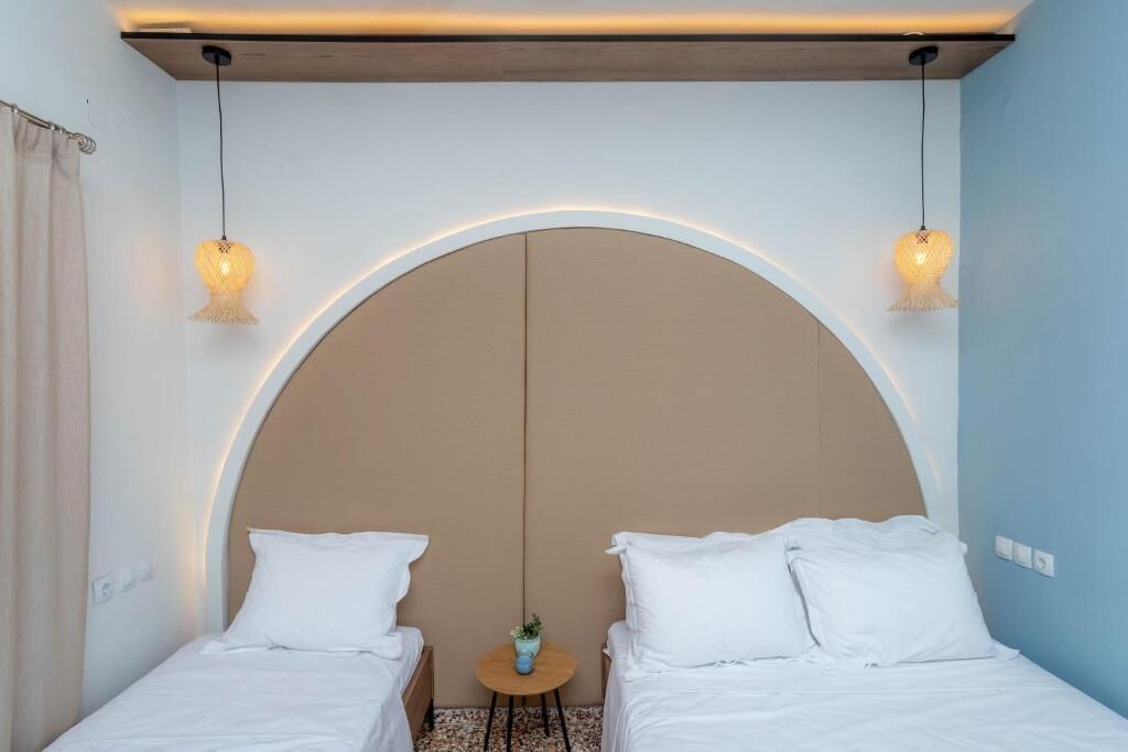 A room with two beds, a round table with a vase, and a large arched ceiling.