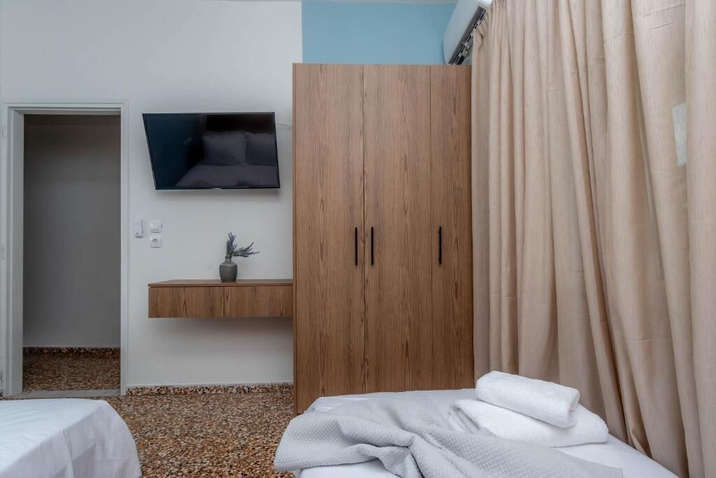 Une chambre à coucher avec un lit, une armoire en bois, un téléviseur fixé au mur et une petite étagère avec une plante.