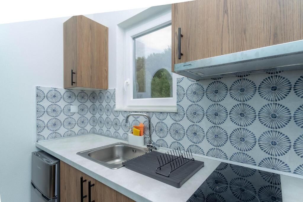 Een keuken met een raam, een decoratieve spatwand en houten kastjes.