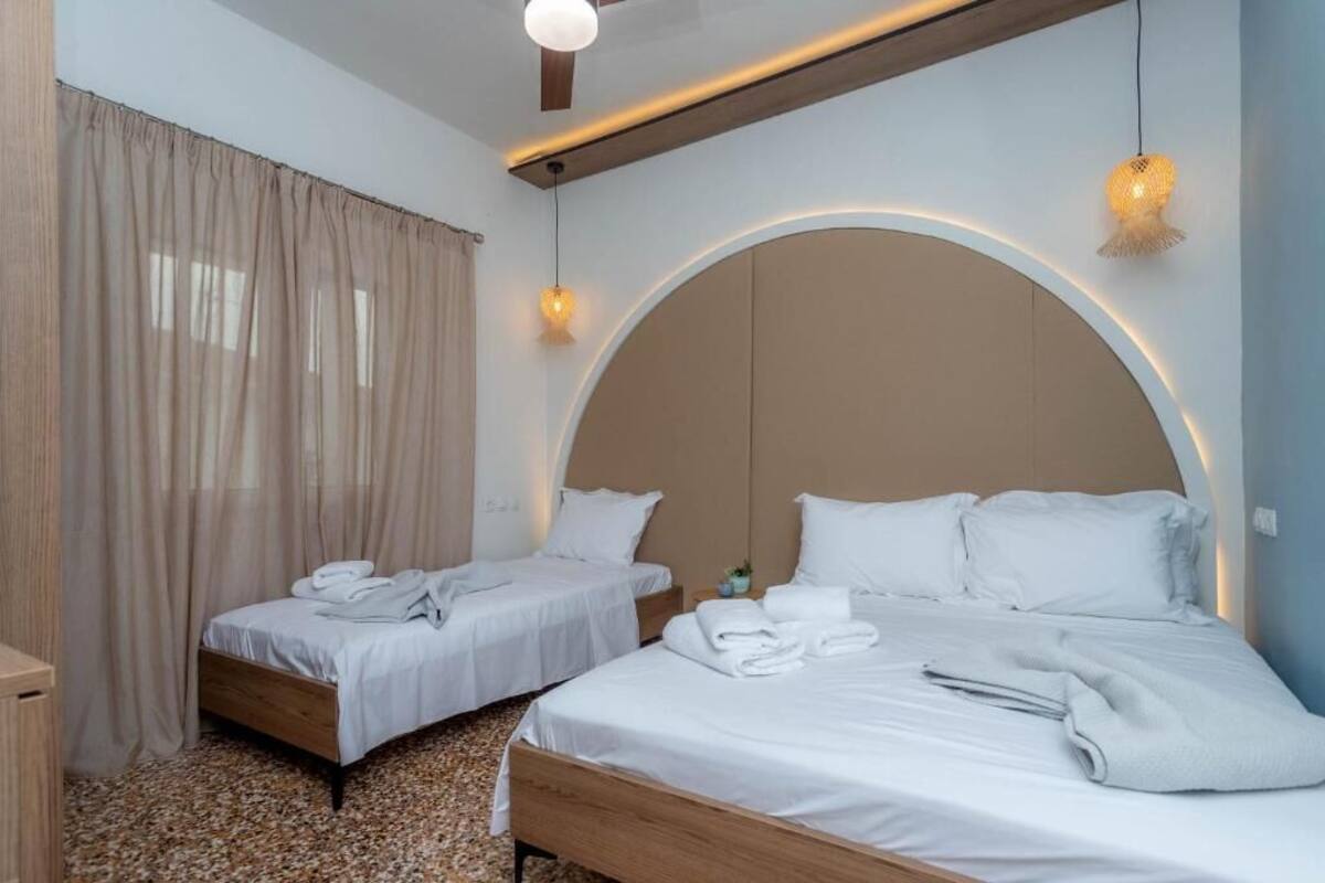 A hotel room with two beds, a wooden headboard, and a large arched window.
