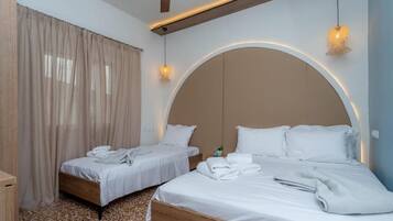 A hotel room with two beds, a wooden headboard, and a large arched window.