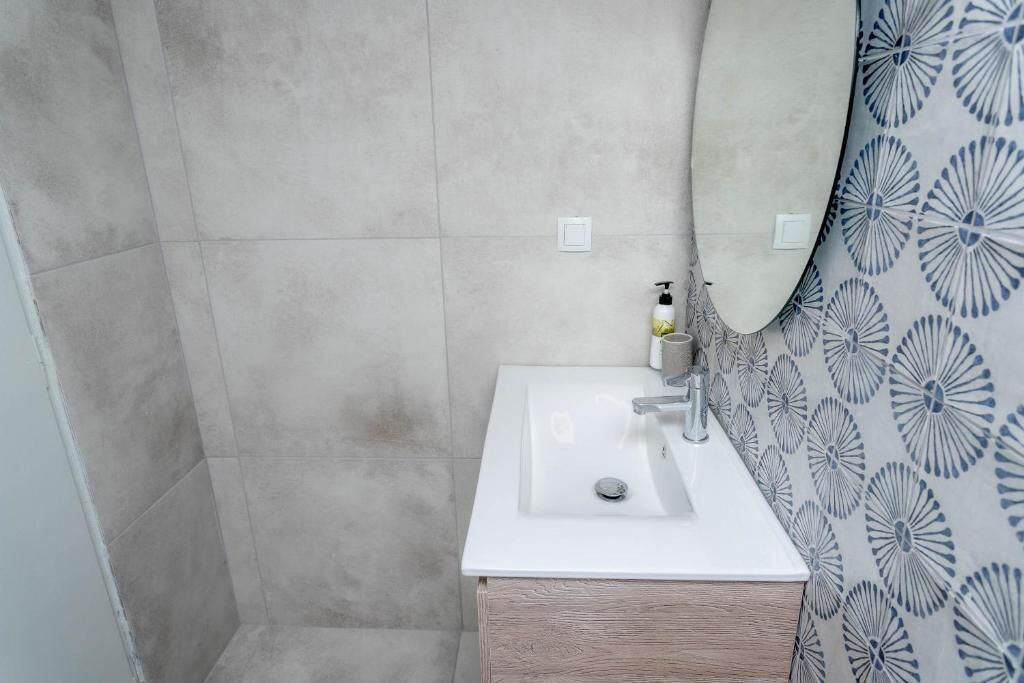 A bathroom with a white sink, a mirror, and a patterned shower curtain.