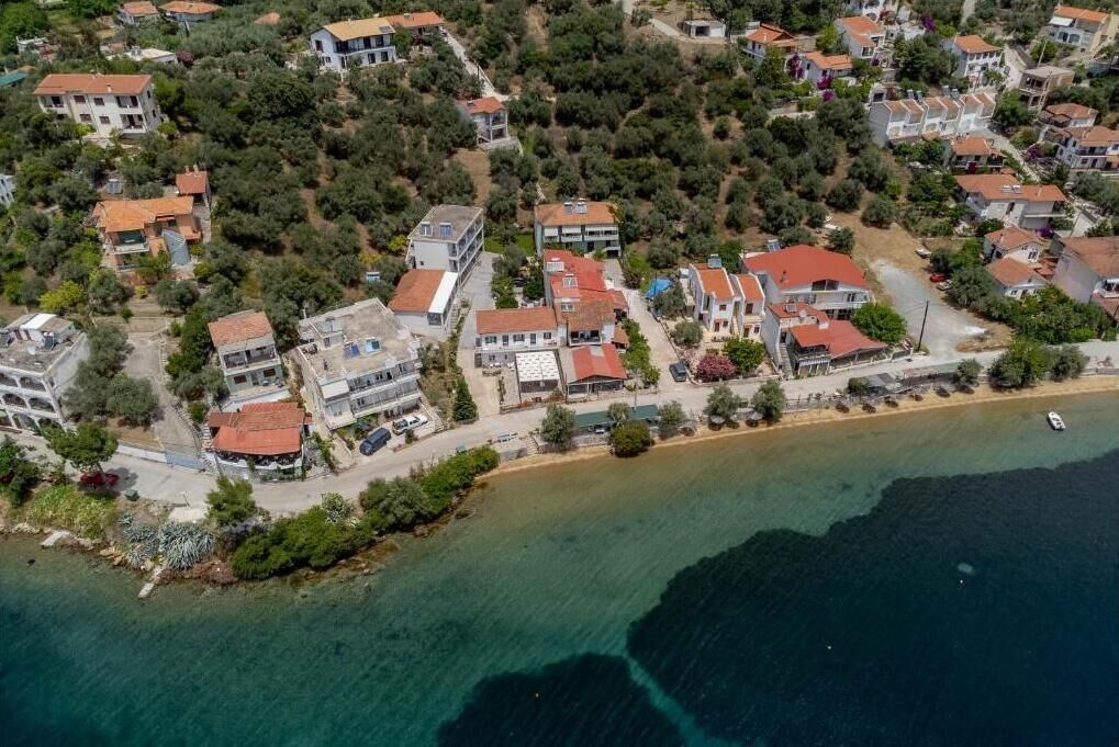 Vue aérienne d’une zone résidentielle côtière, avec des maisons, une plage et un bateau.