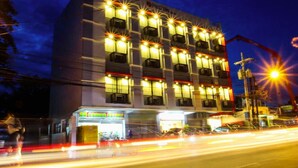 Um hotel de vários andares com fachada moderna, várias varandas e área comercial no térreo.