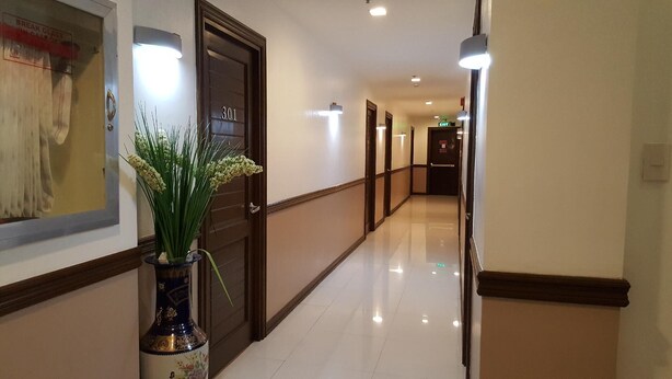 Um corredor de hotel com piso lustroso, uma porta com a inscrição '301' e uma moldura com um quadro na parede.