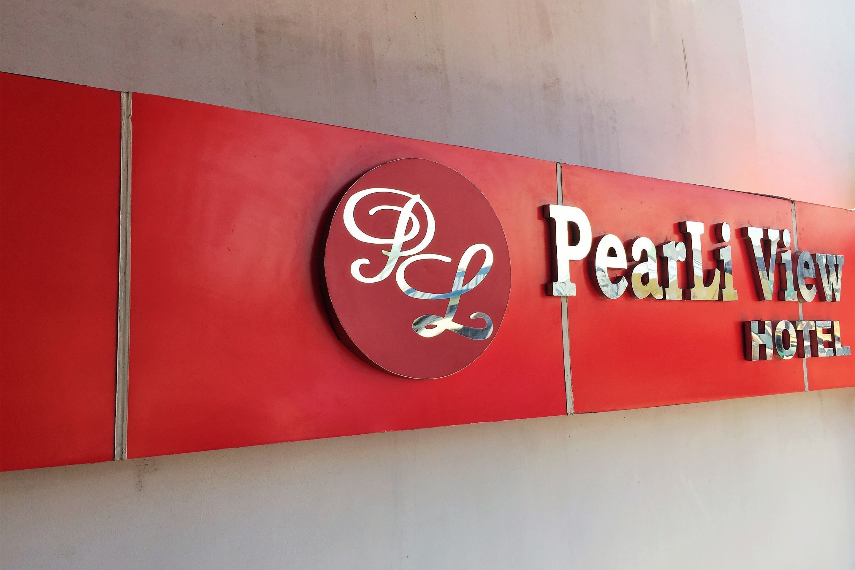 A hotel sign with the name "Pearl View Hotel" and a logo with a stylized 'P' and 'L'.