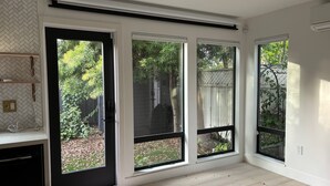 A room with large windows, a built-in shelf, and a visible outdoor area with trees and a fence. - Cozy 1-bedroom/studio with AC, WiFi 5 min from Palo Alto in Menlo Park (Menlo Park)