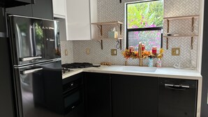 A modern kitchen with a black refrigerator, white countertop, and wooden shelves. - Cozy 1-bedroom/studio with AC, WiFi 5 min from Palo Alto in Menlo Park (Menlo Park)