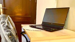 Un ordinateur portable sur un bureau, avec une chaise recouverte de plastique.