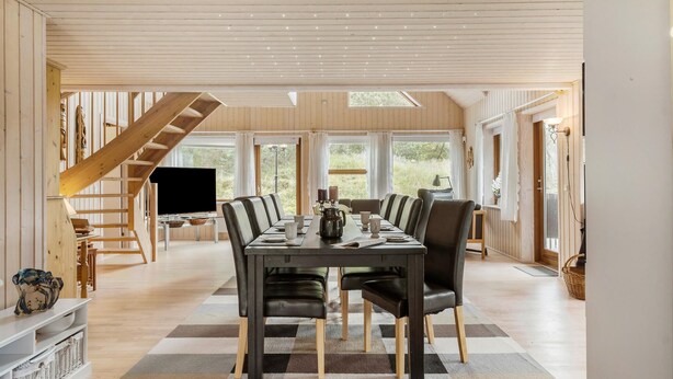 A spacious dining area with a long table, chairs, and a television.