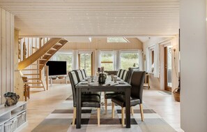 Un grand espace dédié à la salle à manger, avec une longue table, des chaises et un téléviseur.