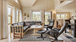 A cozy living room with a sofa, chairs, a coffee table, and a kitchen area visible through an open door.