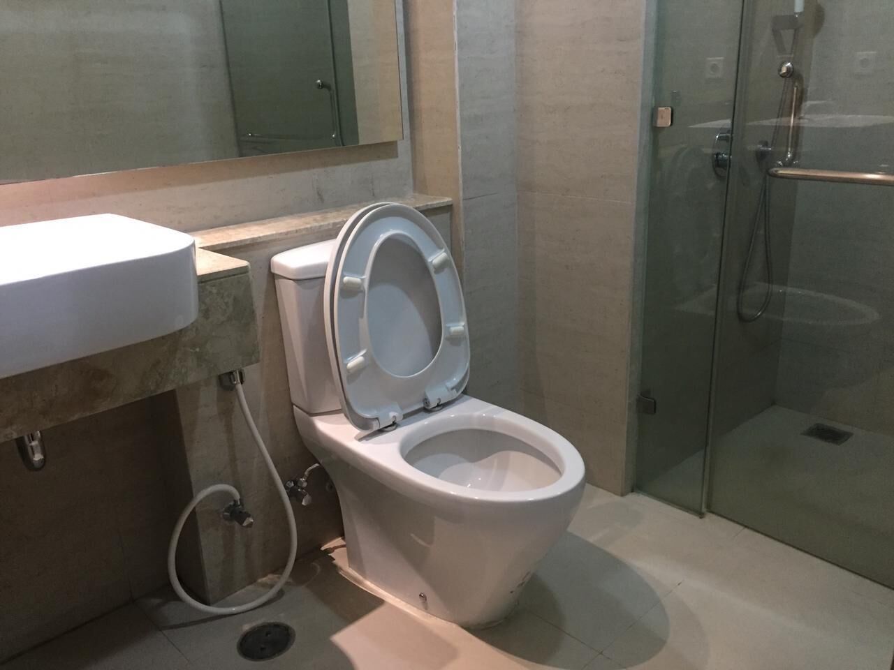 Un baño con inodoro, lavamanos y cabina de ducha de vidrio.
