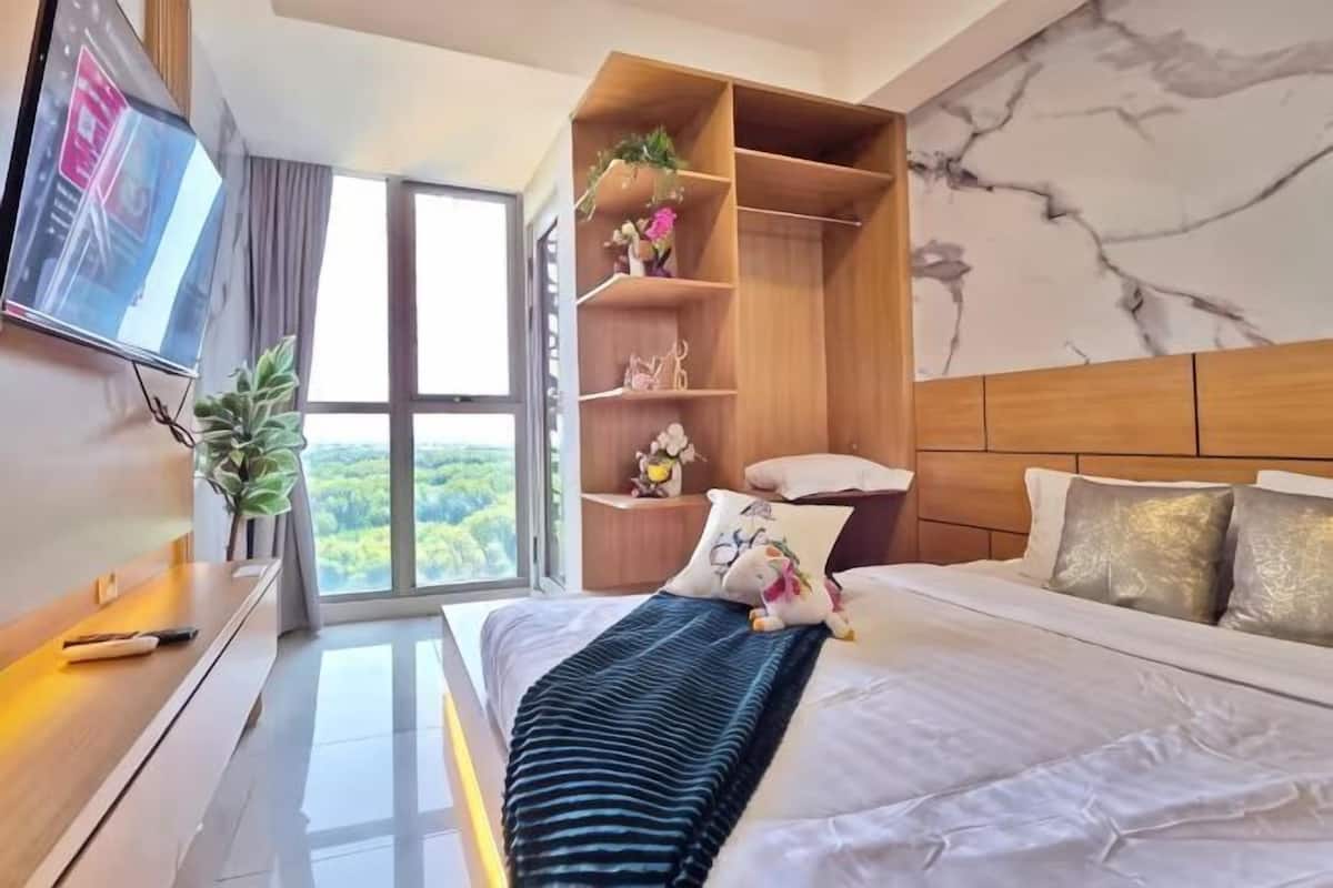 A hotel room with a bed, a TV, a wardrobe, and a large window.