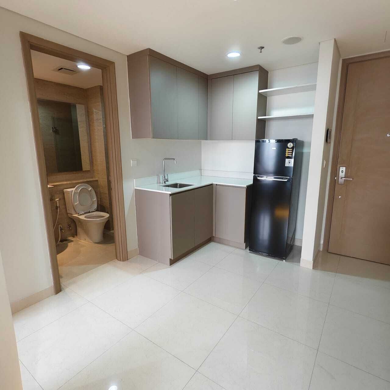 A compact kitchen with a built-in sink, a refrigerator, and a toilet in a corner.