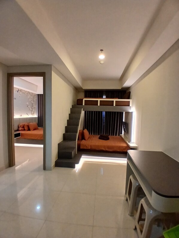A modern interior with a staircase leading to a loft area, a seating area with cushions, and a bar counter.
