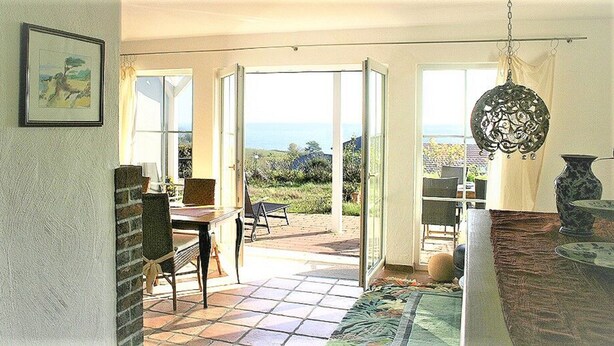 A room with a patio area, a dining table, chairs, and a hanging light fixture.