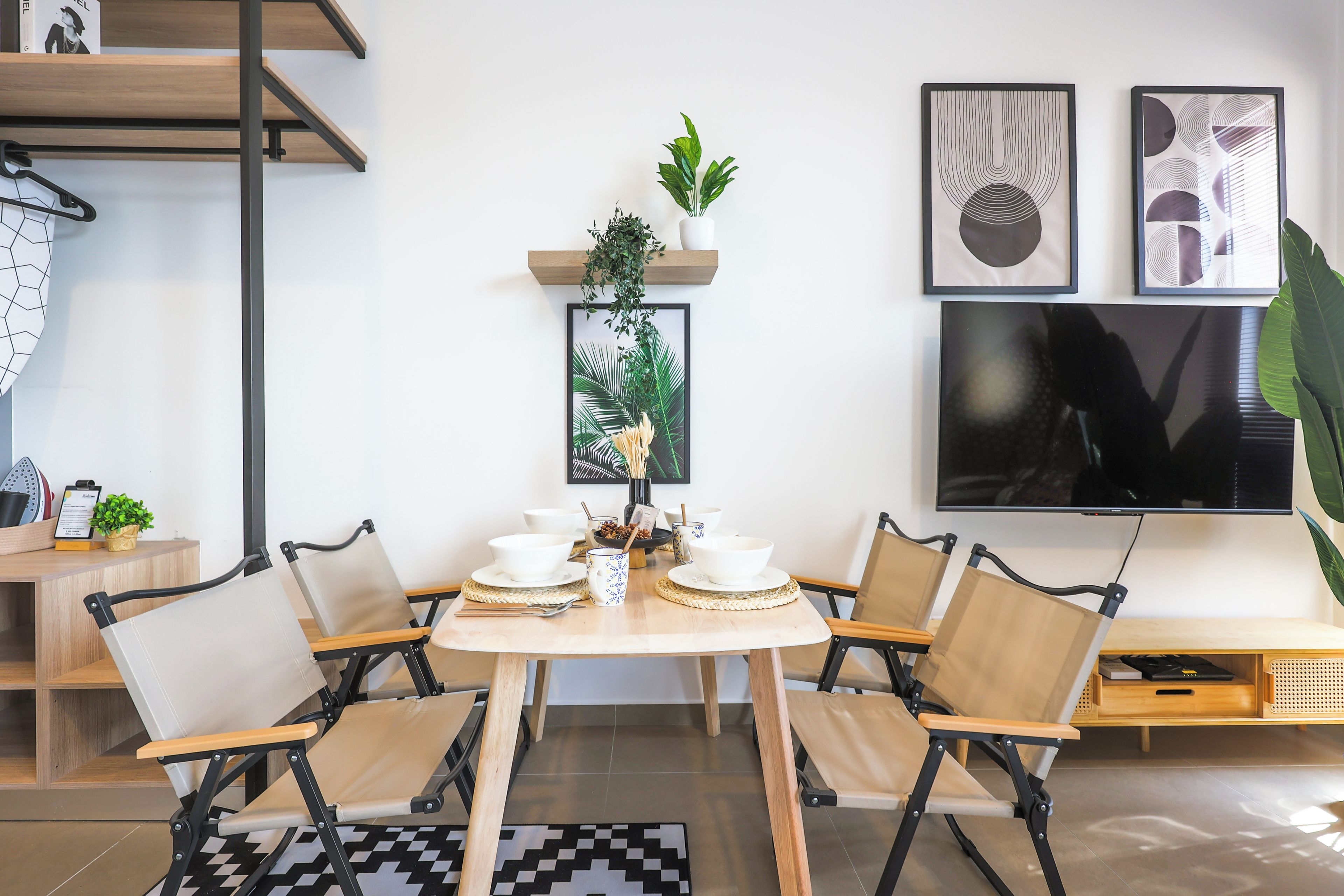 A dining area with a round table, four chairs, and a TV mounted on the wall.