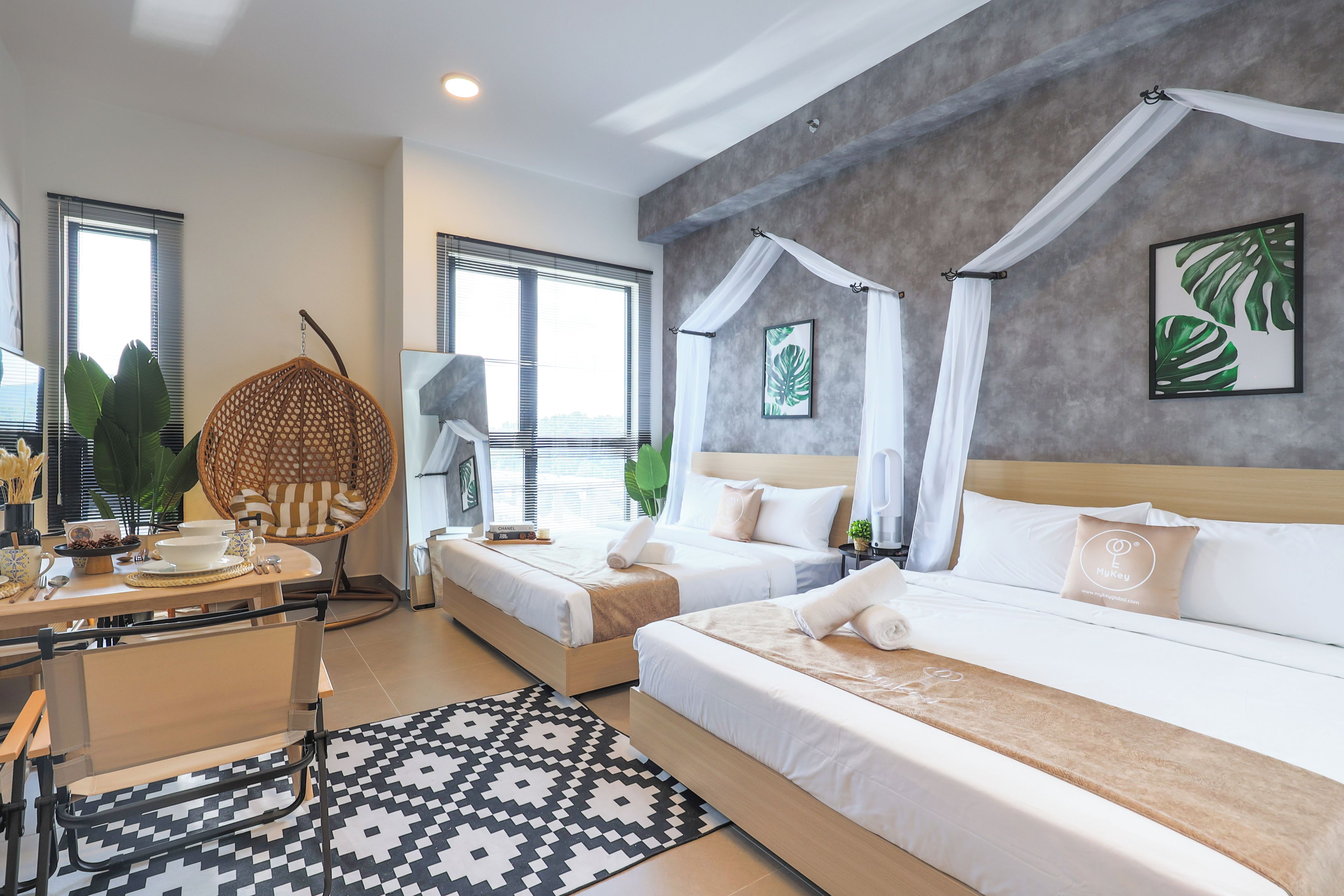 Una habitación de hotel con una cama, una silla, un escritorio con lámpara y vistas al exterior.