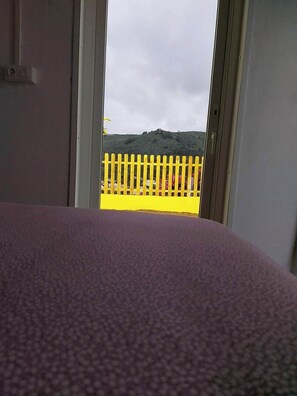 Enjoy a serene view from this hotel room, overlooking a hillside with lush greenery.
