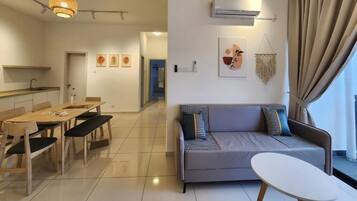 A modern living room with a grey sofa, a dining table with chairs, and a white coffee table.