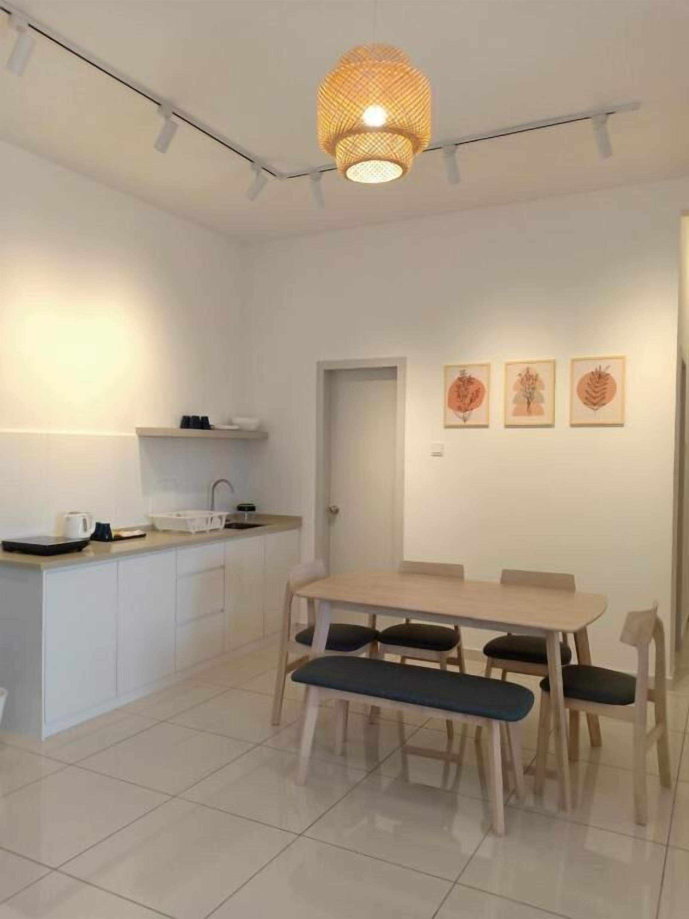 A modern kitchen with white cabinets, a dining table with chairs, and a hanging light fixture.