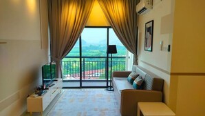 A modern living room with a sofa, a small table, a TV, and a balcony with curtains. - The Horizon by MyKey (Ipoh)