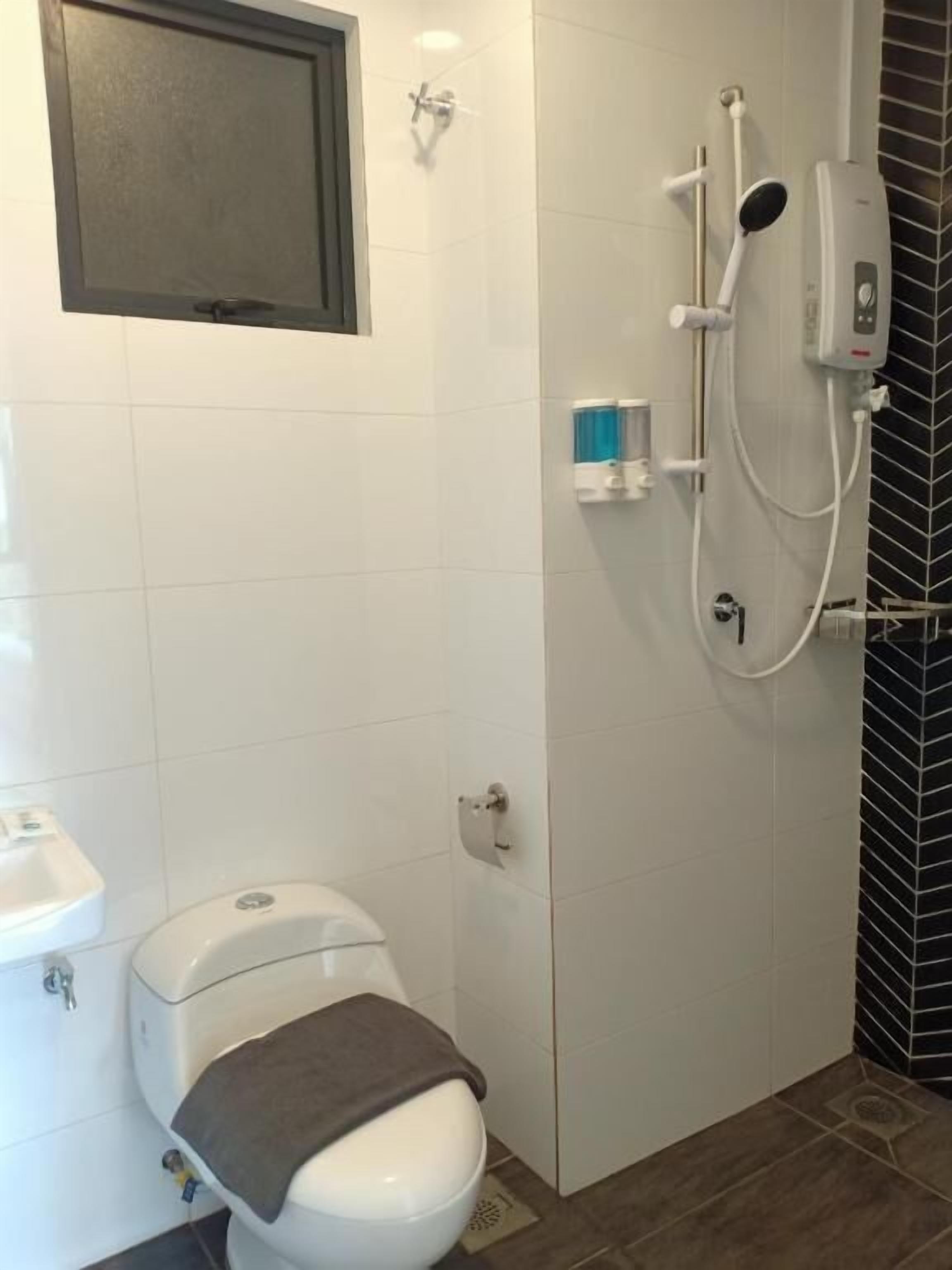 A bathroom with a toilet, a shower area with a handheld showerhead, and a towel rack.
