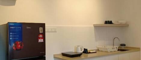 Cocina compacta con un refrigerador negro, un lavamanos y una encimera.